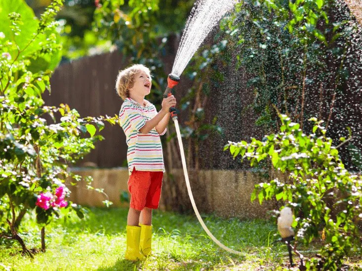 gutt-vanning-blomst-i-hagen-barn-med-PVC-hageslange